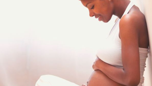 Schwangere, die liebevoll ihren Bauch hält